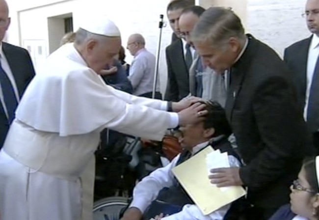 In this image made from video provided by APTN, Pope Francis lays his hands on the head of a young man on Sunday, May 19, 2013, after celebrating Mass in St. Peter’s Square. The young man heaved deeply a half-dozen times, convulsed and shook, and then slumped in his wheelchair as Francis prayed over him. 