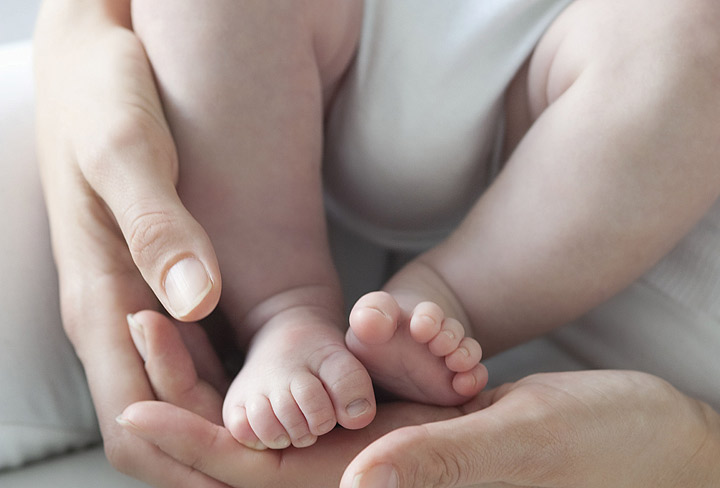 A newborn baby's feet in their parent's hands.