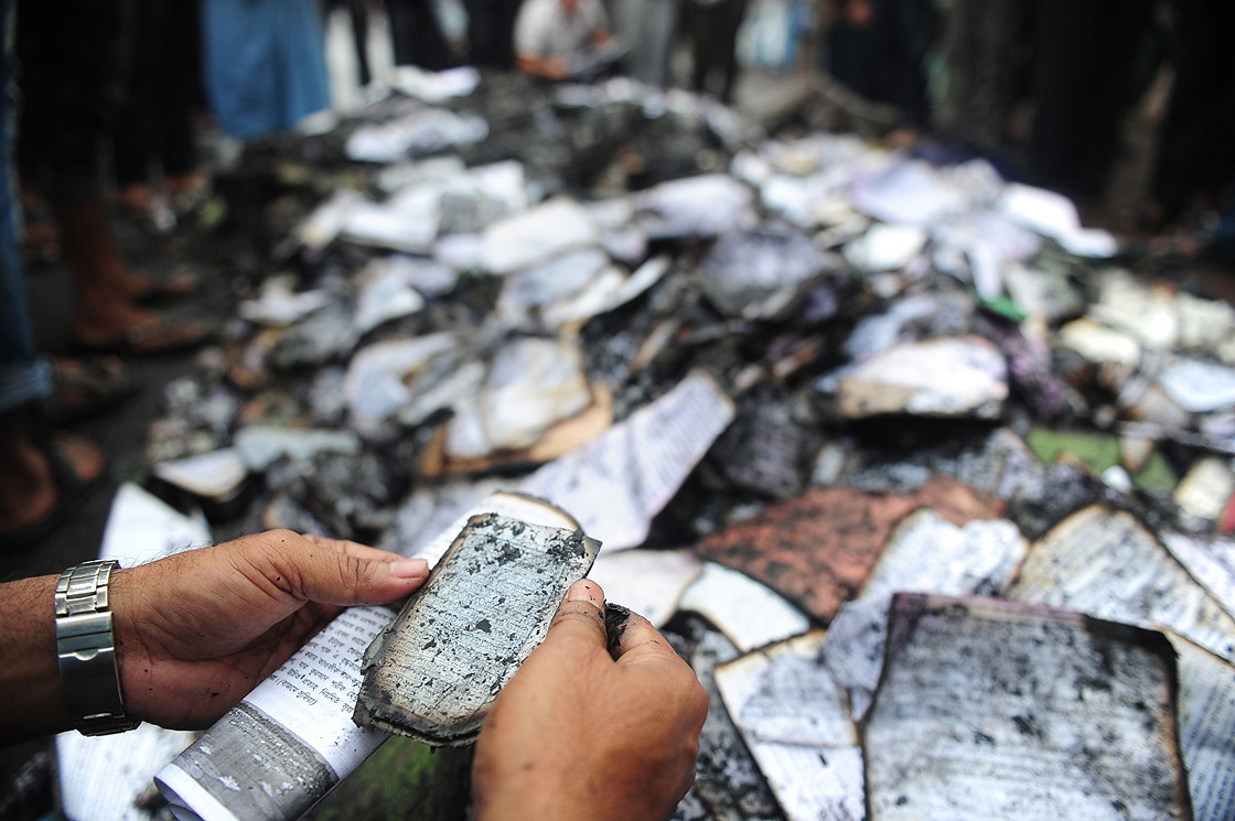 Bangladeshi people look at burnt religious literature including the Holy Quran at shops near the national mosque Baitul Mukarram following a clash between police and Islamists, in Dhaka on May 6, 2013.