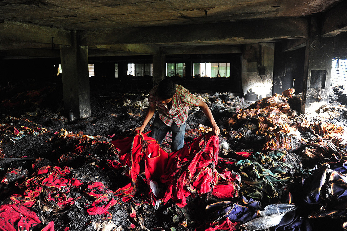 A Bangladeshi garment worker holds up burnt cloth inside a gutted factory in Dhaka on May 9, 2013.