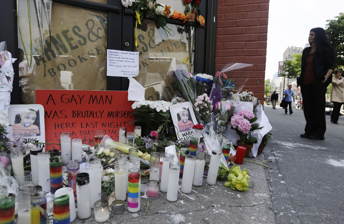 Pedestrians pass a makeshift memorial for 32-year-old Mark Carson, Monday, May 20, 2013, in New York. Police said Elliot Morales yelled anti-gay slurs before shooting Carson point-blank in the face in Greenwich Village.