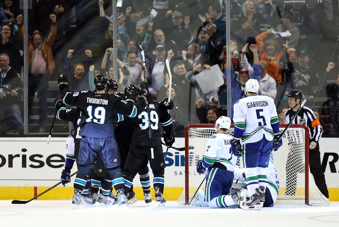 Joe Thornton  and Logan Couture of the San Jose Sharks celebrate around Joe Pavelski (not pictured) after Pavelski scored a third period power play goal past goaltender Cory Schneider, Jason Garrison and Dan Hamhuis of the Vancouver Canucks in Game Four of the Western Conference Quarterfinals during the 2013 NHL Stanley Cup Playoffs at HP Pavilion on May 7, 2013 in San Jose, California. 