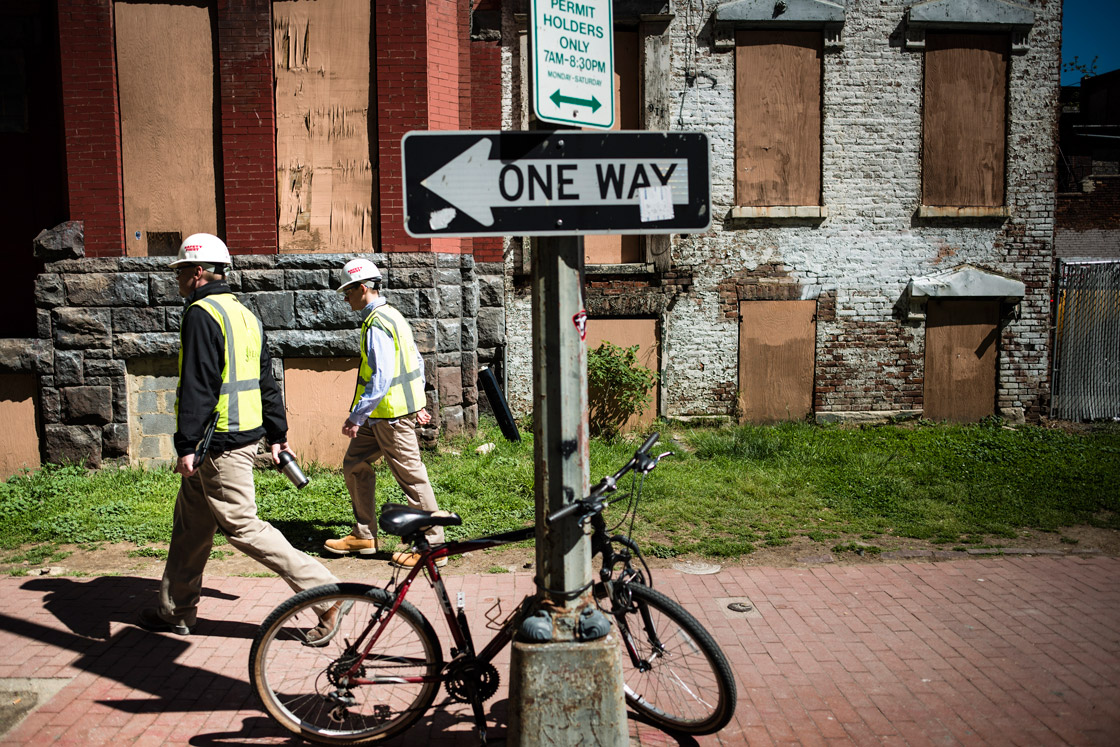 Workers walk past boarded residential buildings while heading to a construction site May 2, 2013 in Washington, DC. 
