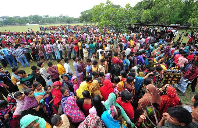 Garment workers employed at Rana Plaza, the garment factory building that collapsed, queue to receive wages from the Bangladesh Garment Manufacturers and Exporters Association in Savar, near Dhaka, Bangladesh, Tuesday, May 7, 2013.