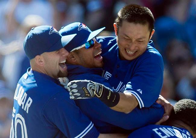 Toronto Blue Jays Munenori Kawasaki (right) leaps into the arms of pitchers Esmil Rogers (centre) and Steve Delabar (left) after hitting the game-winning walk off double against the Baltimore Orioles in AL action in Toronto on Sunday May 26, 2013. 
