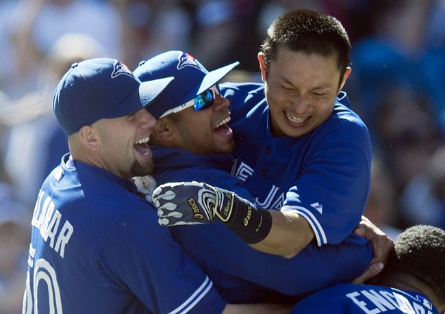 Toronto Blue Jays Munenori Kawasaki (right) leaps into the arms of pitchers Esmil Rogers (centre) and Steve Delabar (left) after hitting the game-winning walk off double against the Baltimore Orioles in AL action in Toronto on Sunday May 26, 2013. 