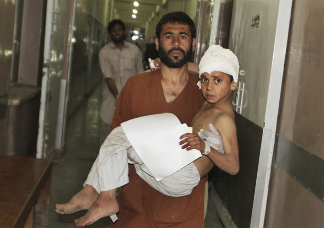 A young injured Afghan boy is carried by his father into the emergency room at the hospital in Kandahar, Afghanistan, Friday, May 17, 2013 after a car bomb exploded inside an elite gated community linked to the family of Afghan President Hamid Karzai. Many people where killed and scores wounded, an official said. (AP Photo/Allauddin Khan).