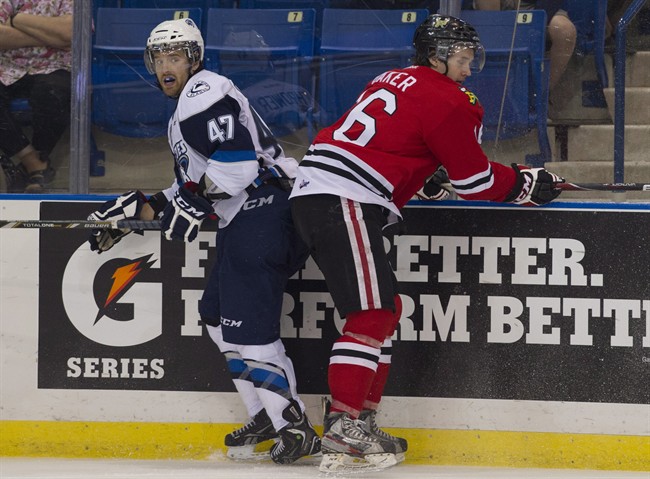 Saskatoon Blades defenceman Dalton Thrower and Portland Winterhawks right winger Joey Baker battle along the boards in Memorial Cup action in Saskatoon, Sask. on Wednesday, May 22, 2013.