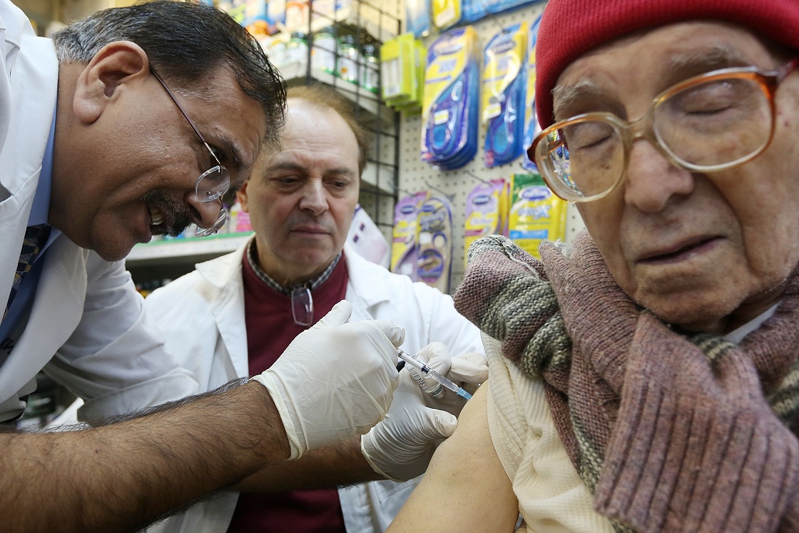 NEW YORK, NY - JANUARY 15: Chief pharmacist Ali A. Yasin (L) injects Juan Castro (R) with influenza vaccine as assistant Agripinno Camiolo looks on at New York City Pharmacy in Manhattan on January 15, 2013 in New York City. 
