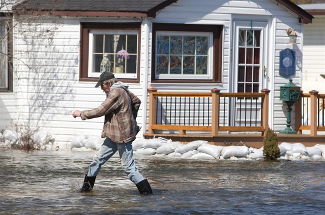 Resident Ben Piels walks past a sandbagged home on Bobcaygeon Rd. in Minden, Ont., on Monday, April 22, 2013. A state of emergency was declared Saturday for this central Ontario town following rapid snow melting and heavy rain. Many residents were evacuated from their homes over the weekend. Officials expect the waters to crest within 24 hours and allow residents back to clean up. 
