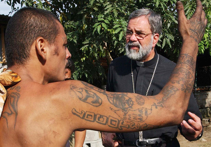File - Romulo Emiliani (R), Archbishop of San Pedro Sula, speaks with a member of the Salvatrucha gang in San Pedro Sula, Honduras, 26 March 2005. 