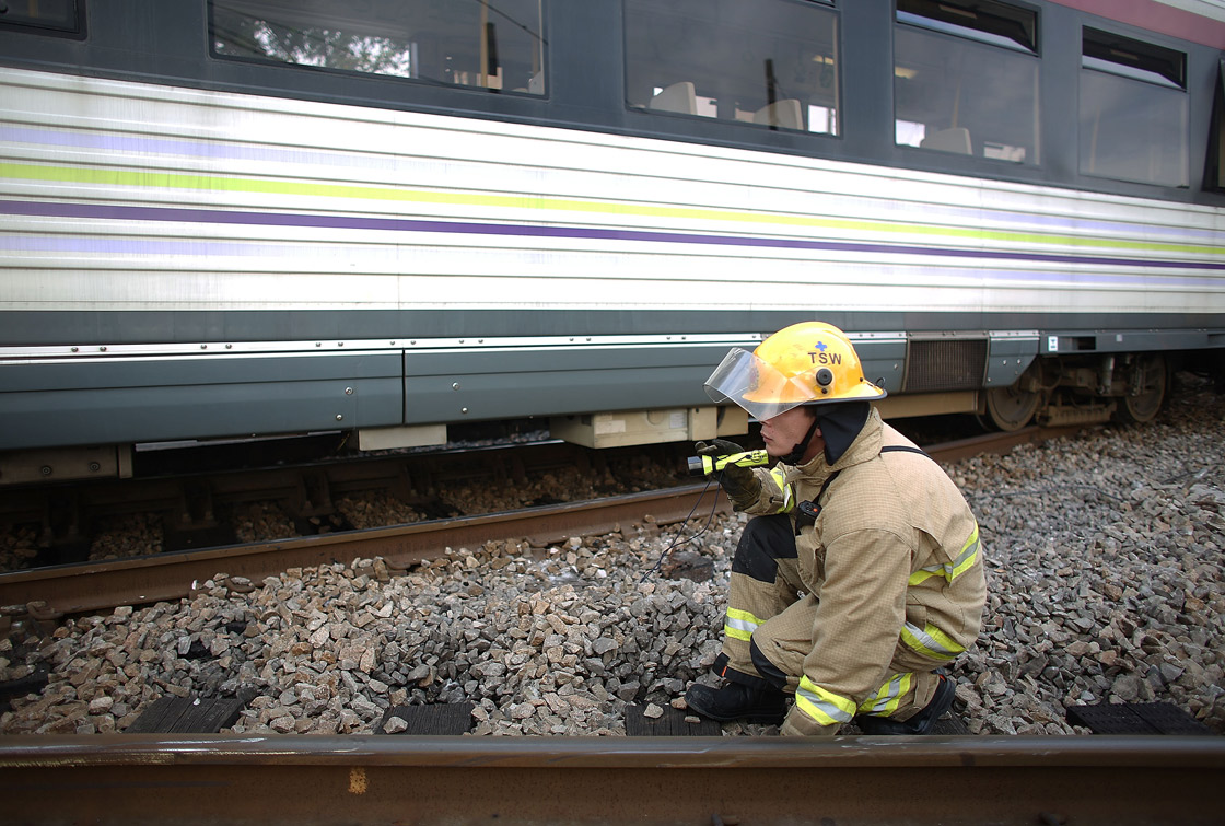 A rescuer searchs for any people trap at the scene after the crash of two light railway trains on 17 May, 2013, near Hang Mei Tsuen Station at Tin Shui Wai in Hong Kong.