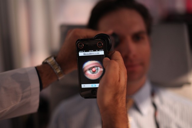 This image provided by TEDMED, shows a medical student preparing to photograph the inside of someone's eye using a special tool that taps a smartphone’s camera during a recent TEDMED conference in Washington. Companies are developing a variety of miniature medical tools that hook onto smartphones to provide almost a complete physical. The hope is that this mobile medicine will help doctors care for patients in new ways, and also help people better monitor their own health. 