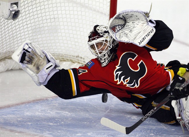 Calgary Flames goalie Miikka Kiprusoff, from Finland, dives on the puck during second period NHL hockey action against the Columbus Blue Jackets in Calgary, Alta., on Friday, March 29, 2013.