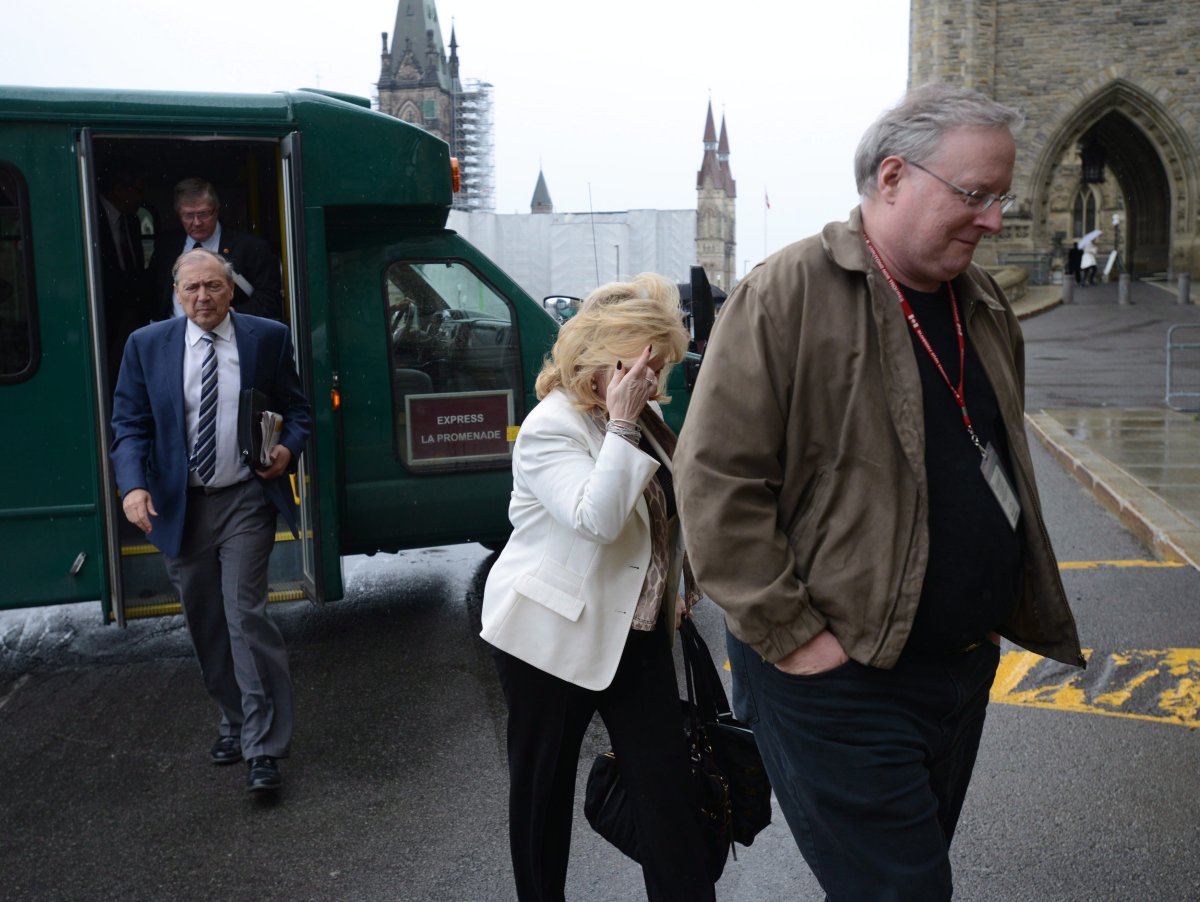 An unidentified man shields Sen. Pamela Wallin from media cameras as she arrives at the Senate entrance on Parliament Hill in Ottawa, Thursday, June 6, 2013.