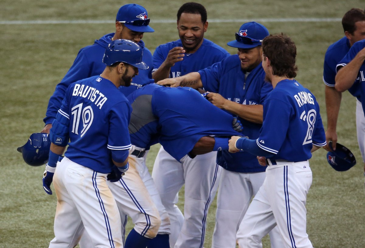 Rajai Davis #11 of the Toronto Blue Jays is embraced by teammates after driving in the winning run in the eighteenth inning during MLB game action against the Texas Rangers on June 8, 2013 at Rogers Centre in Toronto, Ontario, Canada.