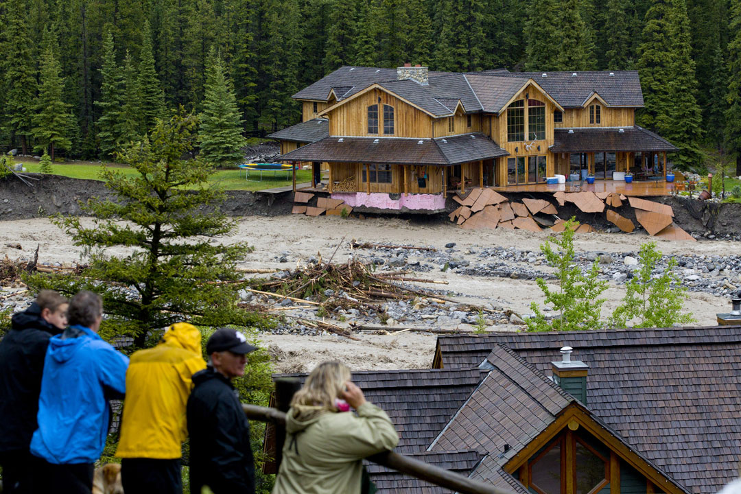 Residents watch flooding along Cougar Creek June 20, 2013 in Canmore, Alberta, Canada. Widespread flooding caused by torrential rains washed out bridges and roads prompting the evacuation of thousnds. (Photo by John Gibson/Getty Images).