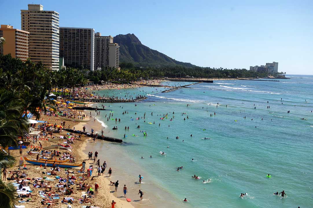 Tourists enjoy sunbathing, surfing, boating and swimming at Waikiki beach in Honolulu.