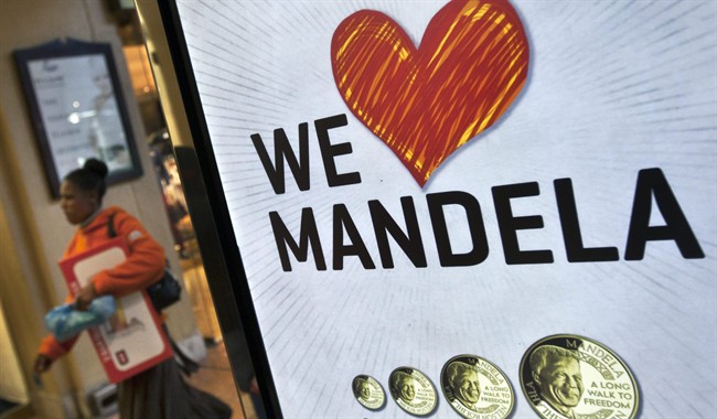 A shopper walks past a sign advertising a shop that sells commemorative coins with the face of Nelson Mandela in the Sandton City shopping centre in Johannesburg, South Africa Tuesday, June 11, 2013.
