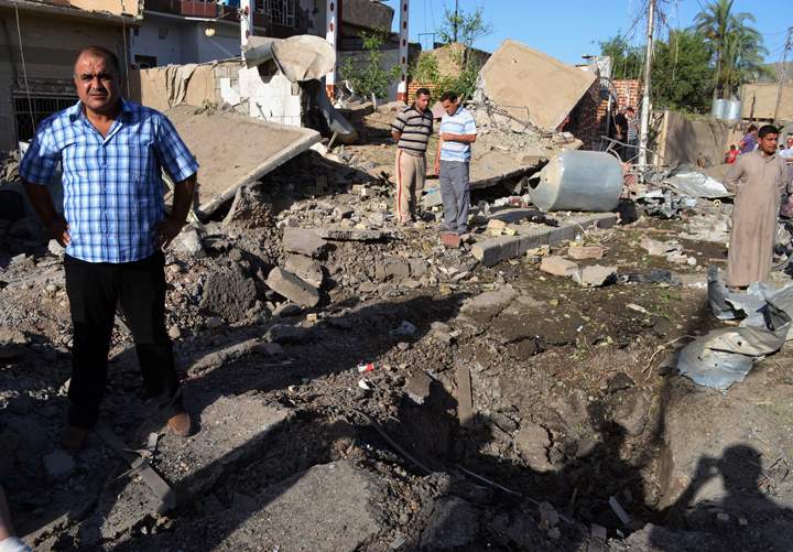 Civilians inspect the scene of two parked car bombs in the early morning at a residential area in Tuz Khormato, 130 miles (210 kilometers) north of Baghdad, Iraq, Sunday, June 23, 2013. 