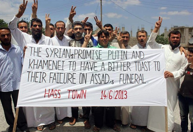 In this citizen journalism image provided by Edlib News Network, ENN, which has been authenticated based on its contents and other AP reporting, anti-Syrian regime protesters hold a banner and flash the victory sign during a demonstration in Hass town, Idlib province, northern Syria, Friday, June 14, 2013. The Syrian government on Friday dismissed U.S. charges that it used chemical weapons as "full of lies," accusing President Barack Obama of resorting to fabrications to justify his decision to arm Syrian rebels. The commander of the main rebel umbrella group welcomed the U.S. move. 