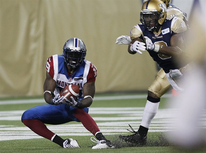 Montreal Alouettes' S.J. Green (19) snags an Anthony Calvillo (13) hail mary pass in the end zone in front of the Blue Bombers' Cauchy Muamba (3) during the second half of their CFL game at Investors Group Field in Winnipeg Thursday.