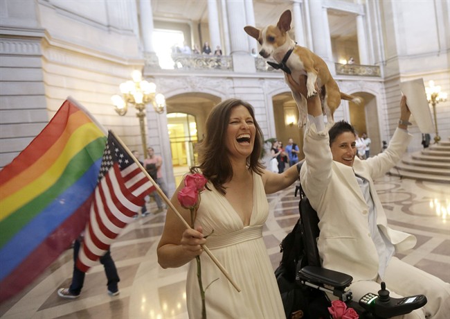 Jen Rainin, left, laughs as her wife Frances holds up their dog Punum after they were married at City Hall in San Francisco, Friday, June 28, 2013. A three-judge panel of the 9th U.S. Circuit Court of Appeals issued a brief order Friday afternoon dissolving, "effective immediately," a stay it imposed on gay marriages while the lawsuit challenging the ban advanced through the courts. (AP Photo/Jeff Chiu).