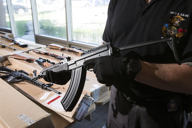 A police officer from the Toronto Police Integrated Gun and Gang Task Force holds a Czech-made assault rifle as police display guns seized during a series of raids for operation "Project Traveller" at a press conference in Toronto on Friday, June 14, 2013. 