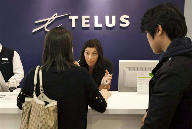 A Telus employee speaks to customers at a Telus Mobility sales location. 