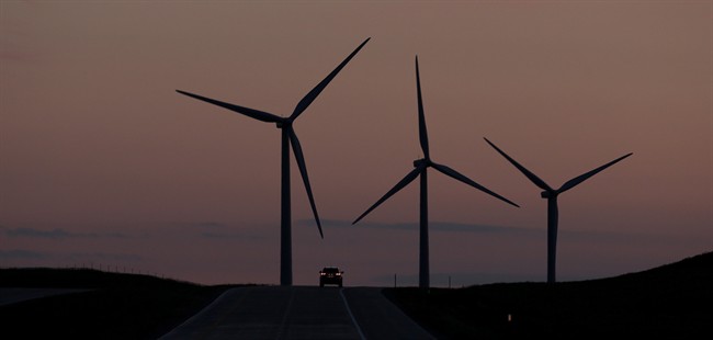A car traveling along Interstate 70 is dwarfed by wind turbines in the Smoky Hill Wind Farm, June 6, 2013, near Wilson, Kan. 