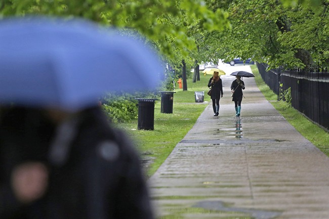 FILE - Pedestrians shield themselves from the rain in downtown Halifax, N.S. on Saturday, June 8, 2013.
