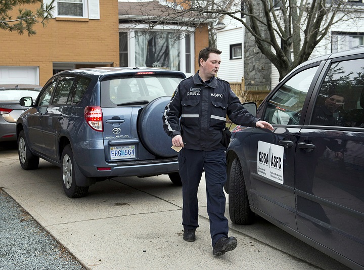 A Canada Border Services Agency officer leaves a residence during an investigation in Dartmouth, N.S. on Wednesday April 10, 2013. A release from the agency states that Hector Mantolino, owner of Mantolino Property Services Ltd., has been charged with 56 counts under the Immigration and Refugee Protection Act for allegedly underpaying foreign workers and telling them to lie to the government about it. 