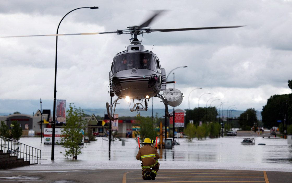 A helicopter carrying evacuated residents lands on a road in High river, Alta. Heavy rains have caused flooding, closed roads, and forced evacuation in High River, Alta., Thursday, June 20, 2013. 