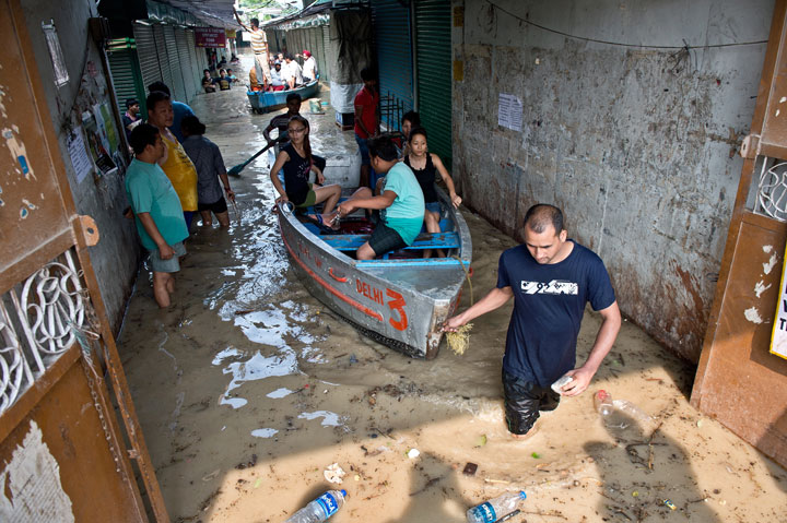 Shopkeepers and residents use boats to traverse through the rising waters of the Yamuna River at the Tibetan market in New Delhi on June 19, 2013.  
