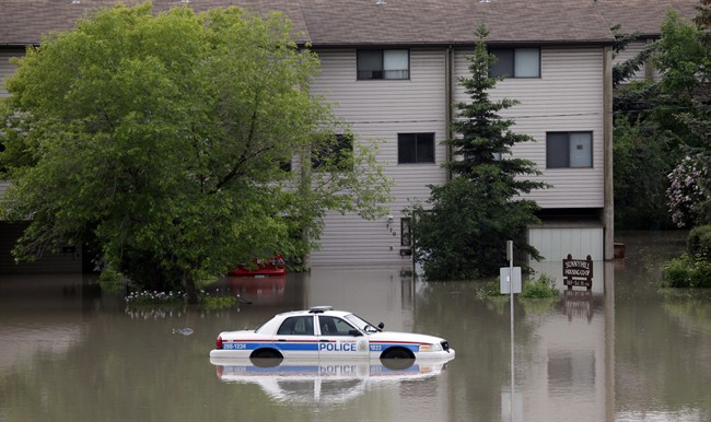A police car sits stuck in a parking lot of an apartment building after heavy rains have caused flooding, closed roads, and forced evacuation in Calgary, Alta., Friday, June 21, 2013.
