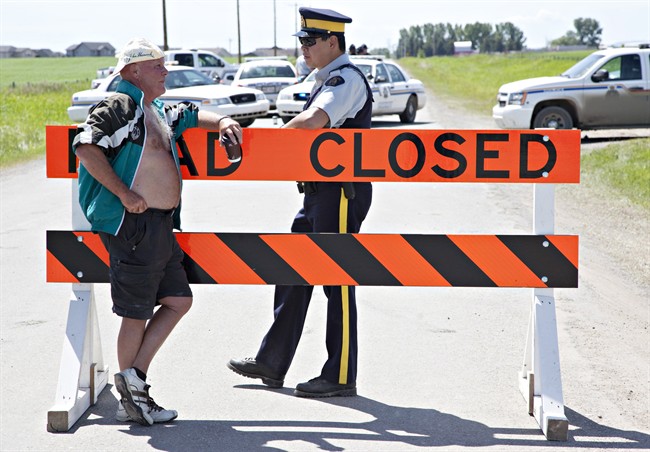 A resident of High River speaks with RCMP at a road block on Tuesday, June 28, 2013 prior to listening to the radio broadcast of the new re-entry plan for evacuees northwest of High River, Alberta.