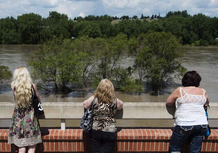 People watch as the South Saskatchewan River rises rapidly and begins flooding in Medicine Hat, Alta., on Sunday, June 23, 2013. 