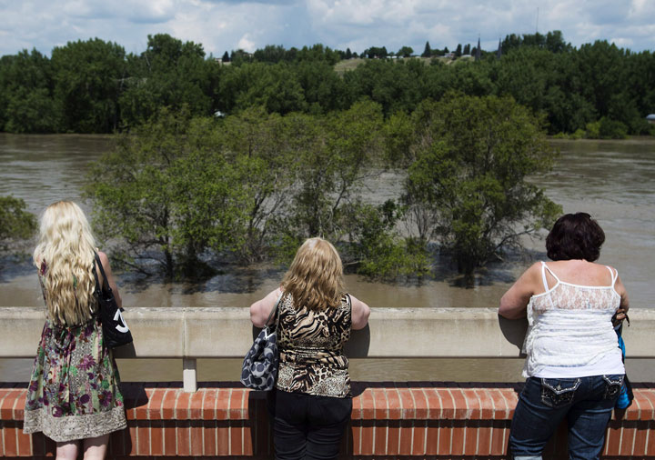 People watch as the South Saskatchewan River rises rapidly and begins flooding in Medicine Hat, Alta., on Sunday, June 23, 2013. 