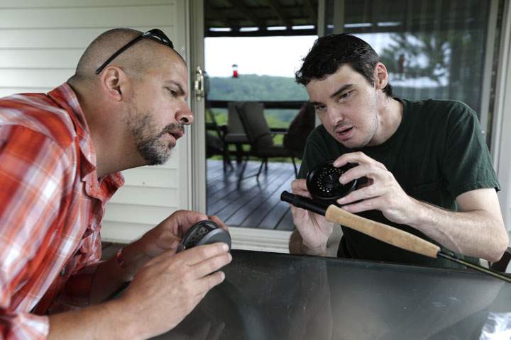 Richard Norris, right, shows friend Andrew Kahle, left, how to load line into a fly fishing rod at Norris' in Hillsville, Va. The man whose face was disfigured by a gunshot spent 15 years as a recluse, but now the 37-year-old is doing things he never would have before. 