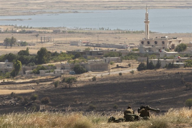 Israeli soldiers armed with a missile launcher sit on a hill overlooking the Syrian village of Al-Mouderia, in the Golan Heights, near the border between the Israeli-controlled Golan Heights and Syria, Friday, June 7, 2013. 