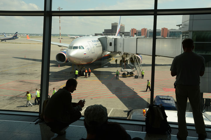 People look the passenger plane, flight SU 150 to Havana, docking to a boarding bridge at the Moscow Sheremetyevo airport on June 24, 2013.  