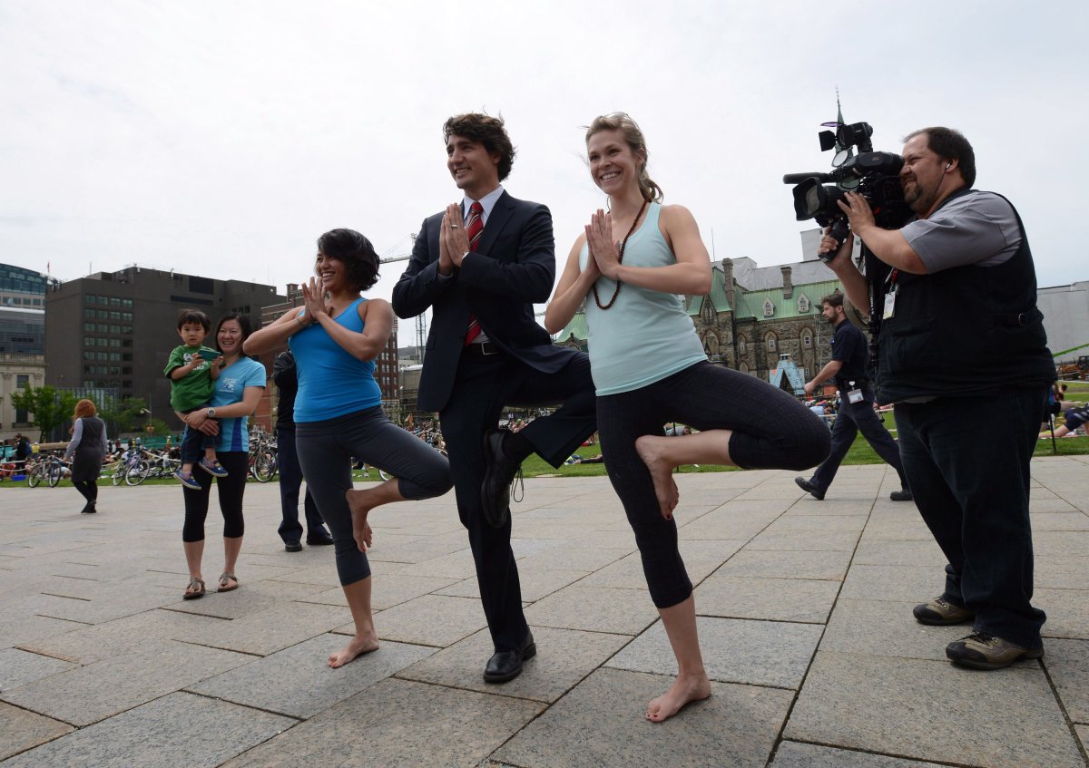 Liberal Leader Justin Trudeau poses with two yoga enthusiasts after holding a press conference on the front lawn of Parliament Hill in Ottawa on Wednesday June 5, 2013. 