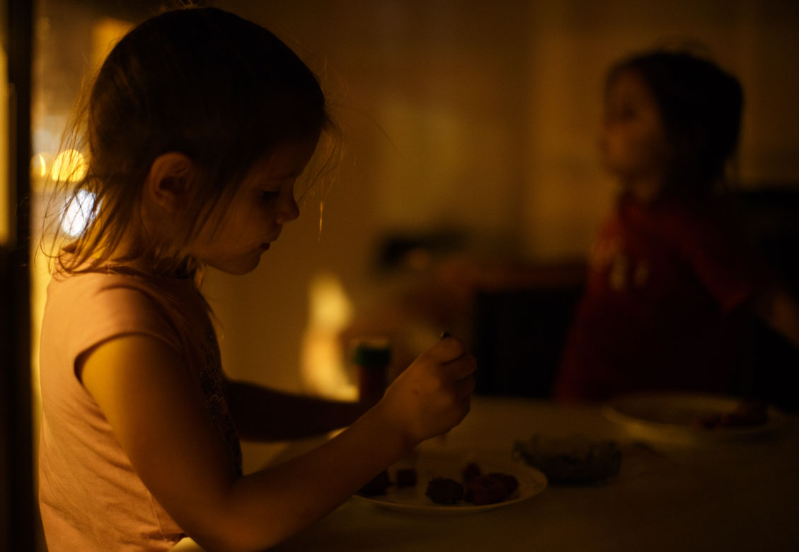 SEVILLE, SPAIN - JUNE 01: Five-year-old twin sisters Kiomara Laguna Arias and Tatiana (L), who were evicted from their home with their parents and brother, eat their dinner lit by the yellow street lights after electricity was cut off, at their apartment, which is part of a complex occupied by the Corrala Utopia community on June 1, 2013 in Seville, Spain.