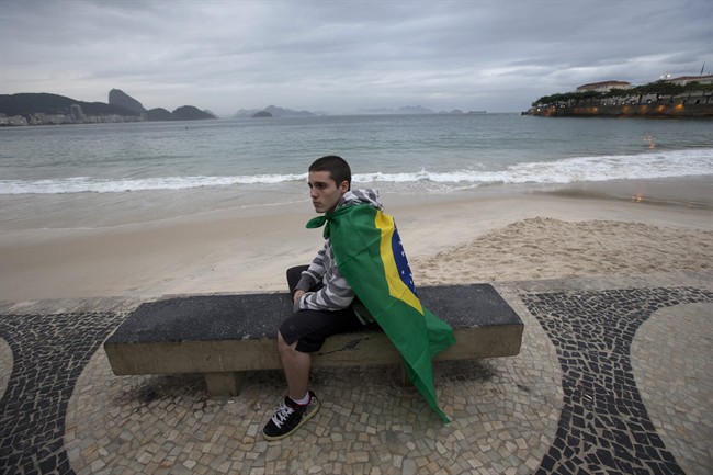 A demonstrator wearing a Brazilian flag on his back sits on a bench in Copacabana during a protest in Rio de Janeiro, Brazil, Sunday, June 23, 2013. 