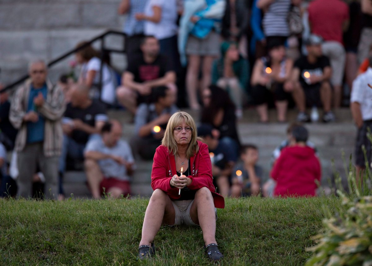 A women sits in front of the St-Agnes church during a vigil to the victims of the train crash Lac-Megantic, Que., Friday, July 12, 2013.