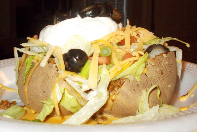 A delicious baked potato stuffed with taco fixings.