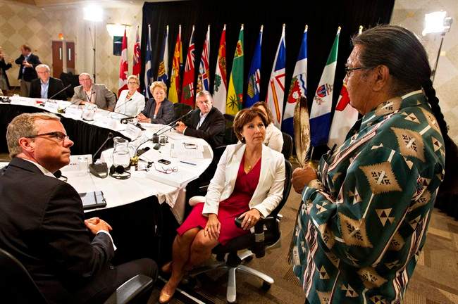 Elder Walter Cooke, right, holds an eagle feather as he conducts the opening prayer for Premiers from across the country and National Aboriginal Organization leaders during a meeting in Niagara-on-the-Lake, Ont., on Wednesday.