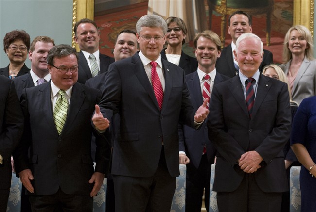 Canadian Prime Minister Stephen Harper gestures as he stands with members of his Cabinet following a swearing in ceremony at Rideau Hall in Ottawa on July 15, 2013. 