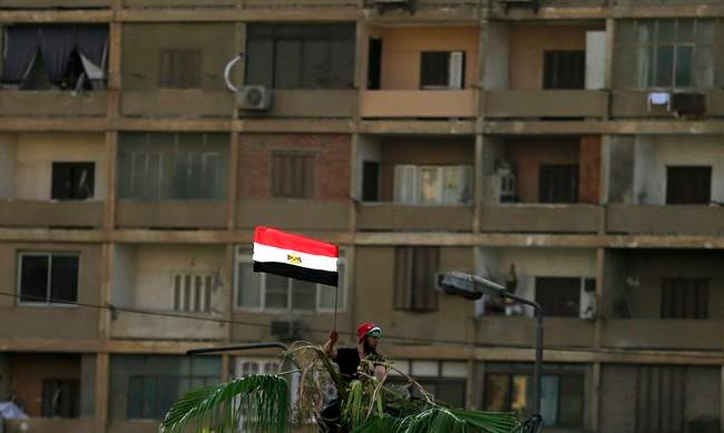 In this photo taken Thursday, July 4, 2013, supporter of Egypt's ousted President Mohammed Morsi holds up an Egyptian flag.