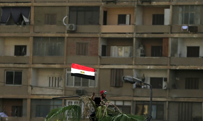 In this photo taken Thursday, July 4, 2013, supporter of Egypt's ousted President Mohammed Morsi holds up an Egyptian flag.